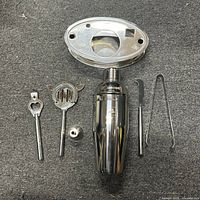 Full set laid out on table showing all 7 components: shaker, strainer, muddler, jigger, opener, knife, tongs