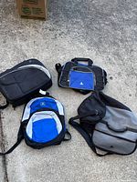Four Sony PlayStation branded bags placed on concrete floor, showing overall wear and tear