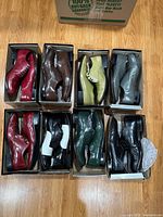 Eight pairs of men's dress shoes in boxes on hardwood floor showing various colors and slight cosmetic wear.
