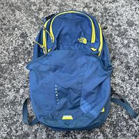 Front view of a blue and green North Face Prewitt backpack with visible wear, loose strings, and yellow zipper accents.