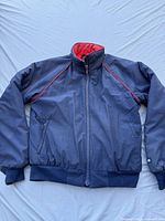 Front view of blue ski jacket with red piping, full zipper, and zippered pockets. Shows overall condition and design.