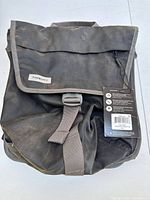 Front and side view of the black Timbuk2 Tandem Pannier bike bag showing flap closure buckle and Timbuk2 logo patch
