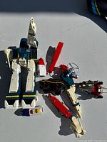 Top down photo showing entire lot including large robot with crane arm, smaller vehicle and spaceship parts scattered around
