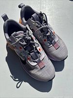 Pair of Women's Nike Air Max 2021 sneakers seen from above, showing toe box, laces, and upper in gray/purple with orange accents.