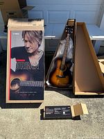 Yamaha Keith Urban guitar in original box next to open shipping container and accessory box