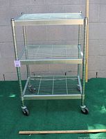 Front view of 3-shelf metal utility cart with caster wheels, showing overall structure and materials.