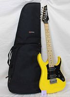 Yellow Ibanez 3/4 size electric guitar leaning against black Protec soft gig bag case. Full guitar and case visible to show overall condition and style.