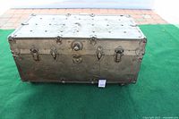 Front view of the brown metal treasure chest showing rivets, clasps, and lock mechanism