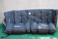 Three black folded and rolled Eddie Bauer self-inflating camping pads resting against a black cushioned surface, showing the attached black straps and white Eddie Bauer logo on each pad.