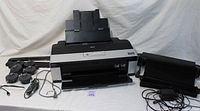 Wide front view of Epson Stylus Photo R2880 printer with multiple spool holders, power cord, USB cable, and roll cutter accessories on white backdrop.