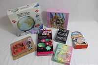 Lot of games, puzzles, and craft kits displayed on a white surface showing all included boxed items.