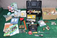 Wide shot of diverse handyman supplies including tools, light bulbs, hardware components, a toolbox, and various small miscellaneous items.