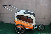 Side view of the orange and white Leonpets pet stroller showing mesh windows and large wheels.