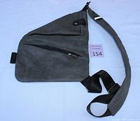 Full view of the grey triangular nylon crossbody bag with multiple zipped compartments and padded adjustable strap laid flat
