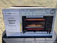 Box of Mainstays 4-slice toaster oven showing features like fit for 9-inch pizza, adjustable temperature to 450°F, and toast, bake & broil settings.