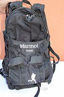 Front view of the black Marmot T2500 backpack showing the embroidered logo and flap pockets.