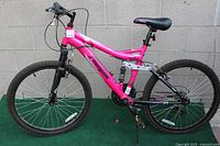 Full side view of the pink Mongoose Ledge 2.1 mountain bike showing frame, tires, suspension, and LED wheel lights.