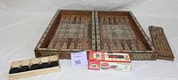 Photo showing the closed wooden folding game board with mother of pearl inlay, checkers pieces in tray, and box of Bicycle playing cards.