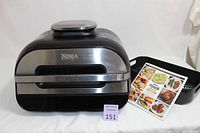 Front view of Ninja Foodi Smart XL air fryer unit with recipe booklet and accessories on side