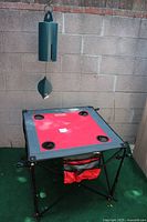 Red Creative Outdoor folding table with four cup holders and four wine holders visible, frame in black metal and fabric seating in red color.