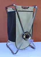 Full view of SimpleHuman X-frame hamper showing beige fabric bag with black mesh side pocket and chrome frame.