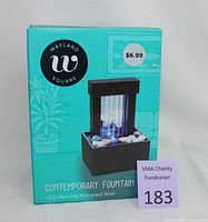 Front view of the unopened box showing the product image and branding, with price sticker and charity tag.