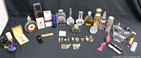 Wide view of assorted vintage perfume bottles and atomizers on black surface showing a variety of sizes and designs.