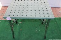 Full view of the foldable work table showing the top surface with circular clamp holes in a grid pattern.