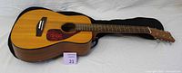 Yamaha 3/4 junior acoustic guitar lying on soft case, showing full body and neck.