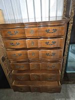 Front view of five-drawer French Provincial chest showing serpentine drawers and brass-tone pulls