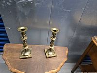 Pair of brass candlesticks on table, full view