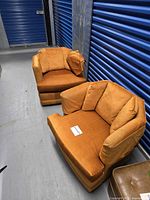 Pair of orange upholstered swivel club chairs in storage aisle