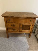 Front view of wooden antique dry sink showing drawers and cabinet door