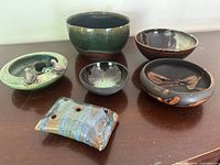 Photo showing all items on a wooden surface including four pottery bowls, the frog plant dish, and ceramic incense holder