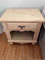 Front view of the bedside table showing the drawer with metal handle and open bottom shelf.
