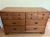 Front view of solid wood dresser showing six drawers with two different styles of drawer pulls, straight edges, and panel back style.