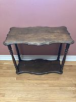 Front view of the solid wood vintage end table showing scalloped edges on top shelf and spindle legs.