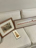 Lot of three framed art pieces on beige couch: Third edition Fifty-eight People and a Tree print, vintage watercolor of European street scene and pressed flowers art.