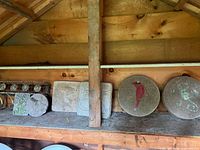 Photo of six cement garden stones, two circular with embossed bird and floral designs, four square with floral/nature patterns, placed on a wooden shelf.