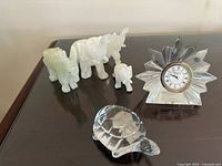 Image showing all items in the lot on a dark surface: four marble animal figures (donkey and three elephants), clear glass turtle, Waterford Crystal starburst clock.