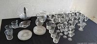 Full display of the collection showing multiple glassware items including plates, bowls, pitchers, and glasses on a black tablecloth.