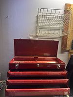 Red metal Mastercraft tool kit with closed drawers and top lid open, showing interior compartment.