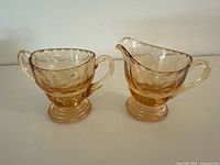 Front view of amber glass cream and sugar set on white surface