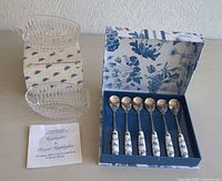 Set includes 6 teaspoons with ceramic floral handles in original blue floral box, two clear lead crystal spoon/fork holders in original box with fabric lining plus leaflet.