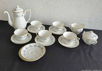 Full set of Royal Worcester bone china coffee set items arranged on black surface: coffee pot, 5 cups with saucers, 3 extra saucers, creamer, and covered sugar bowl.
