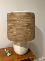 Full view of lamp showing white ceramic base and woven shade