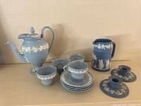 Overall group showing teapot, 4 cups, 4 saucers, pitcher, and 2 candle holders in the Wedgwood blue jasperware with white relief.