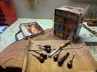 Photo showing woodcarving tools, Lee Valley apron, Kuny’s tool organizer, and woodcarving magazines on workbench