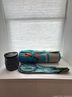 Group view: rolled foam mat, badminton racket with cover, insulated cylindrical bag