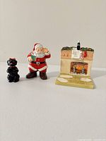Front view of separate Santa shaker, black dog, and fireplace shaker
